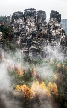Rock formations and misty weather in colorful autumn forest at Saxon Switzerland in Germany