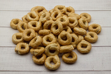 Taralli alla pugliese with extra virgin olive oil on wooden background. Traditional italian snack Taralli