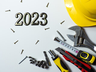 2023 with construction tools, yellow hard hat on white background with copy space. New Year and...
