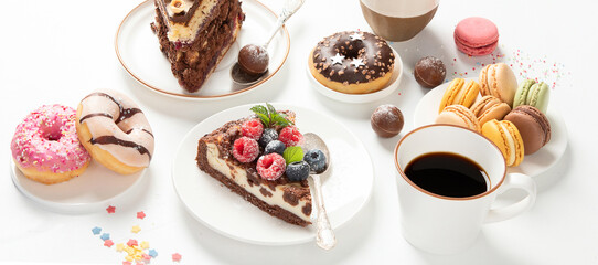 Table with various cookies, donuts, cakes,  coffee cups on white  background.