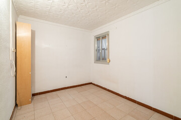 Empty spacious room with window and dirty walls in an old flat before renovation.