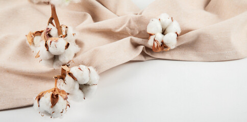 Beige napkin and cotton branch. The concept of natural ecological fabrics.