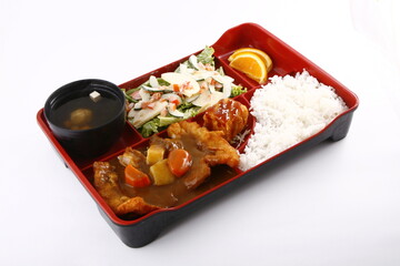 Bento box meal with chicken teriyaki curry, miso soup, vegetables and rice