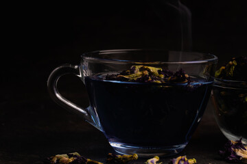 Butterfly pea flower tea in a clear glass on a black background.