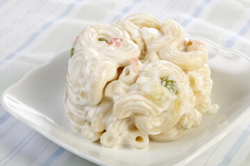 A scoop of macaroni salad with peas and carrots