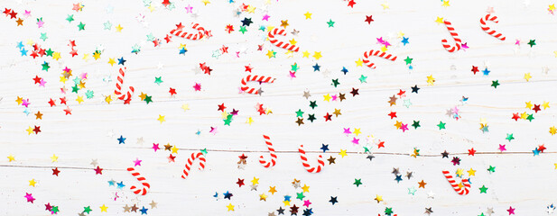 Christmas background with candy canes and multicolored sequins on blue wooden background