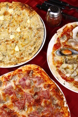 Top shot of three flavors of pizza - all-meat, seafood and four cheese