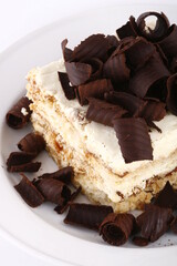 Closeup of a tiramisu slice with chocolate curls on top