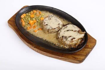 Creamy filet mignon with peas and carrots served on a sizzling plate