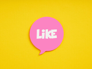 The word like on pink speech bubble on yellow background. Social media concept.