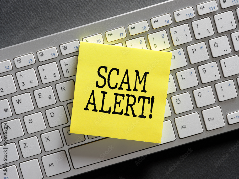 Poster the word scam alert written on a sticky note paper on computer keyboard. scam warning or fraud notic