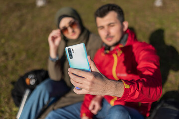 A young happy Muslim couple are taking selfie while hiking on the mountain.