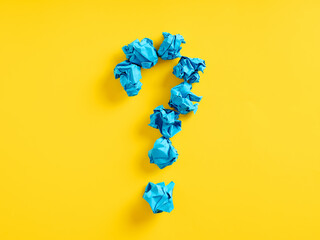 Question mark symbol made out of blue crumpled papers on yellow background. Query, problem,...