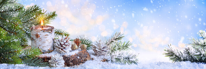 Christmas or New Year Holiday composition with burning candle, pine cones and fir tree. Winter holiday background.