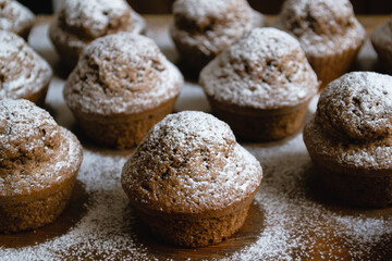 Close-up of delicious baked chocolate cupcakes on a wooden board and sprinkled with white powdered sugar