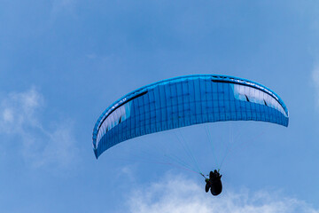 Paraglider flying in the blue sky