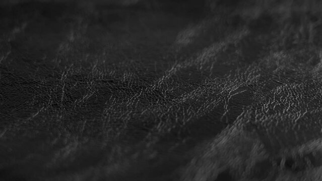 Glossy wrinkled natural black leather close-up. Rotation