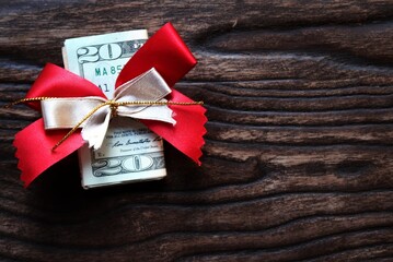 Money gift on wood copy space background, cash dollar banknote with beautiful red gold ribbon,...
