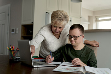 Caucasian man with down syndrome learning with his mum at home