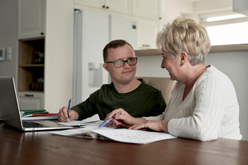 Caucasian man with down syndrome learning with his mum at home