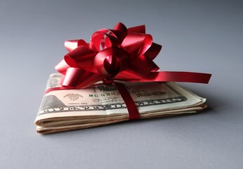 Dollar cash money with with red ribbon and gift bow on gray background , concept of gift money or...