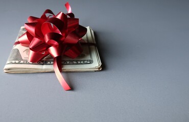 Dollar cash money with with red ribbon and gift bow on gray background , concept of gift money or bonus