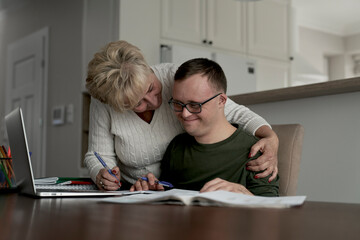 Mother hugging caucasian man with down syndrome while learning at home