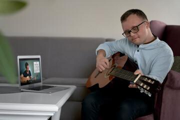 Adult caucasian man with down syndrome learning how to play at guitar