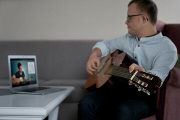 Adult caucasian man with down syndrome learning how to play at guitar