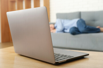 Laptop against young woman sleeping on sofa