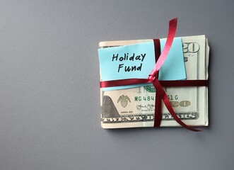 Cash dollar money in red ribbon with hand written blue note HOLIDAY FUND - concept of money saving...