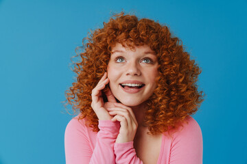 European woman with red curly hair smiling and looking upward