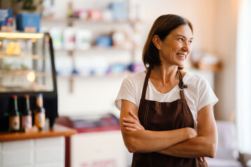 White mature barista woman smiling while working in cafe