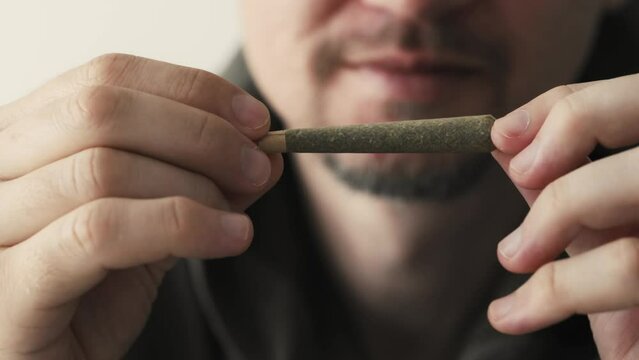 Young man holding marijuana joint in hands. CBD cannabis close up.