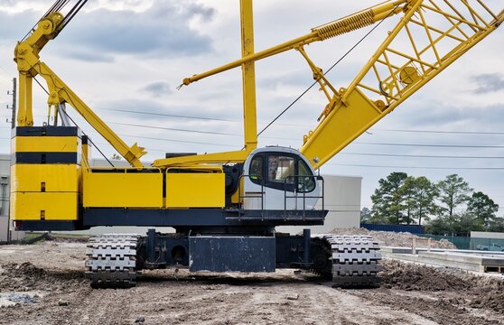 Crawler crane isolated front view on a construction site with focus on the machine deck, counterweight and treads.