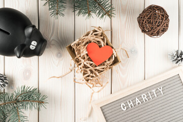 Black piggy bank for donation and present box with red paper heart postcard, top view. Decorative...