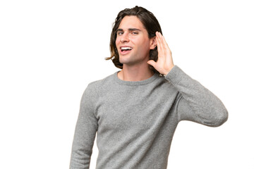 Young caucasian man isolated on green chroma background listening to something by putting hand on the ear