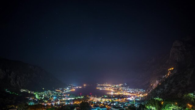 Amazing time lapse video with starry night sky above the picturesque Bay of Kotor with illuminated buildings and harbor.