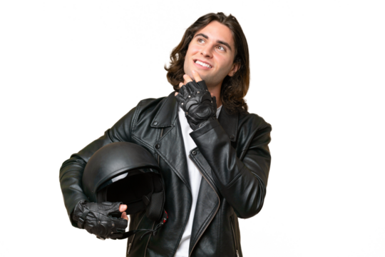 Young handsome man with a motorcycle helmet isolated on green chroma background looking up while smiling
