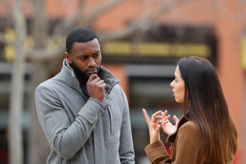 Suspicious man listening a woman talking in winter