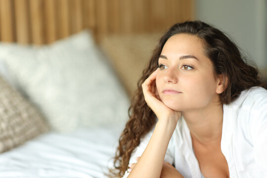 Pensive woman on a bed looking away