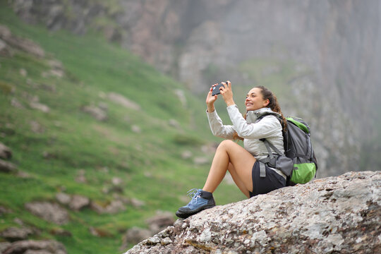 Trekker taking photos with smartphone in the mountain