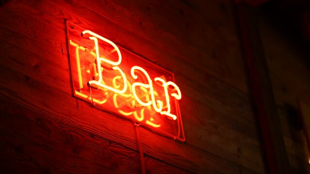 Bar florescent light sign on business entrance in RED color with wooden surface advertising business in handheld motion