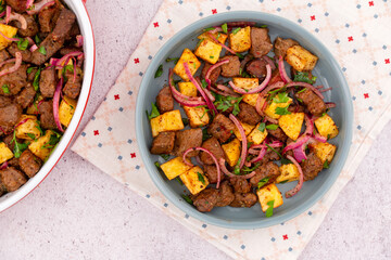 Turkish Edirne liver, traditional fried beef liver and potato with red onion and parsley on blue plate, stone background colorful napkin, top view flat lay photo