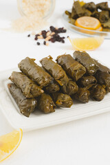 Authentic Turkish sarma with rice, black currant, fresh herbs, olive oil, vegan sarma stuffed grape leaves, close up vertical portrait food photo selective focus