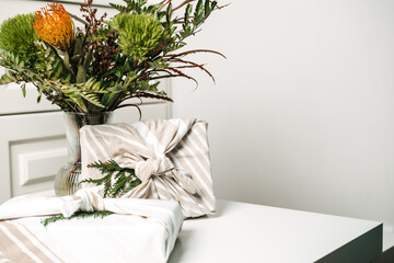 Eco friendly furoshiki wrapping cloth gift boxes. Holiday gifts christmas background with Furoshiki gift boxes wrapping in zero waste style and green plant bouquet web banner