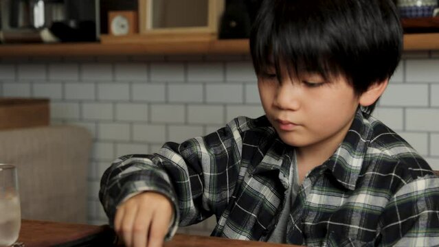 Asian boy playing backgammon at home.