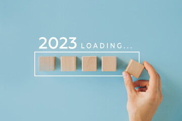 Female hand putting wooden cube for countdown to 2022. Loading year from 2022 to 2023. New year start concept