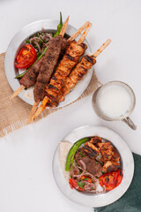 Traditional Turkish chicken shish kebab and Adana Kebab, made with minced lamb and spices, served with lavash, ayran buttermilk and roasted pepper tomato and red onion top view flat lay photo 