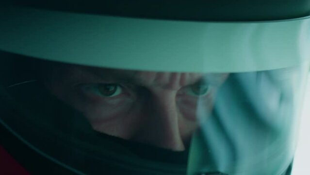 ECU Portrait of sports car driver in protective helmet racing on a speedway. Fast speed, motorsport. Daytime shot